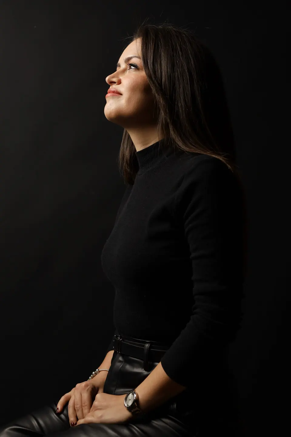 Portrait of a woman seated in low light, looking away in thought