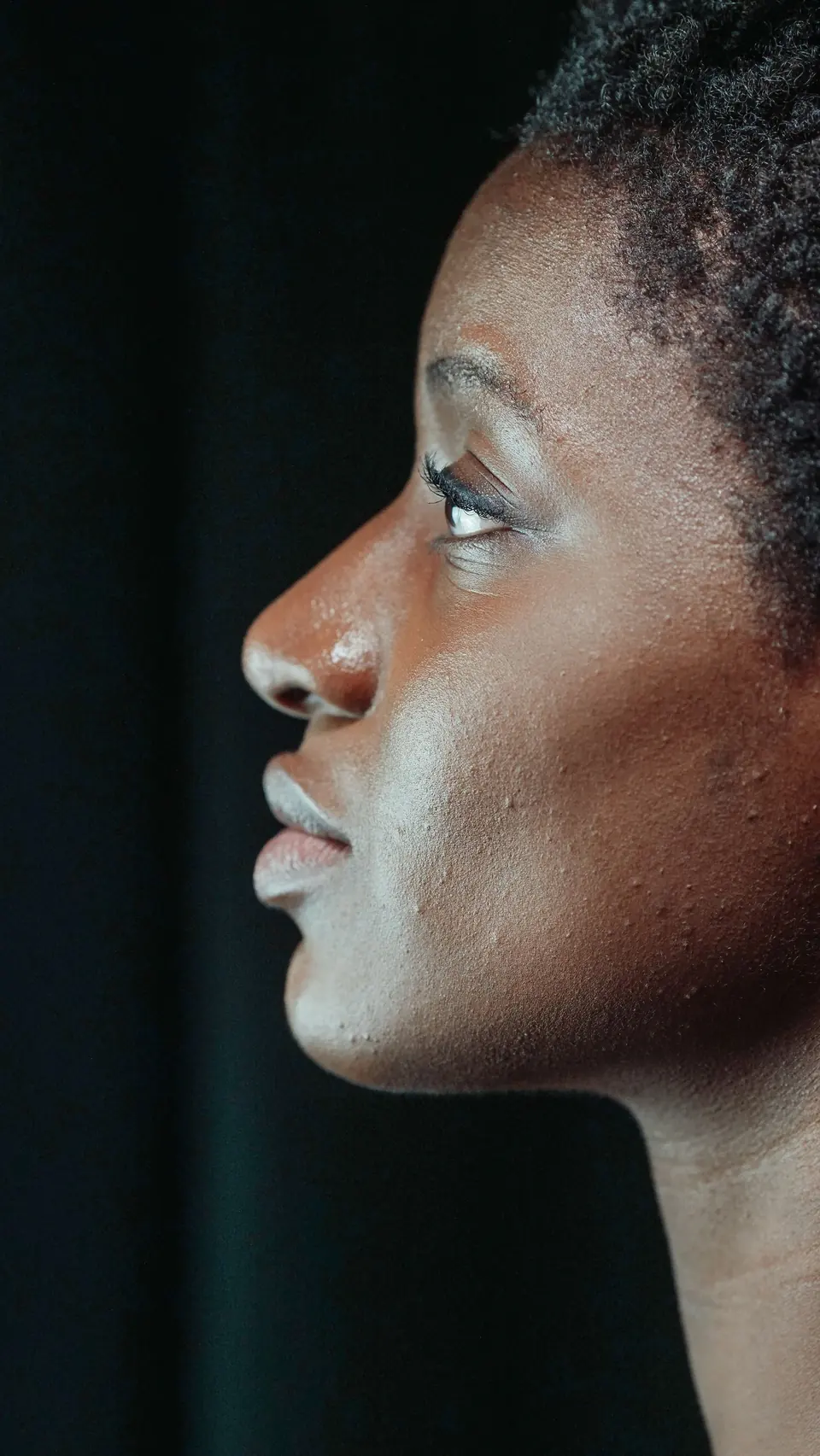 Studio profile portrait of a woman lit from one side against a dark background