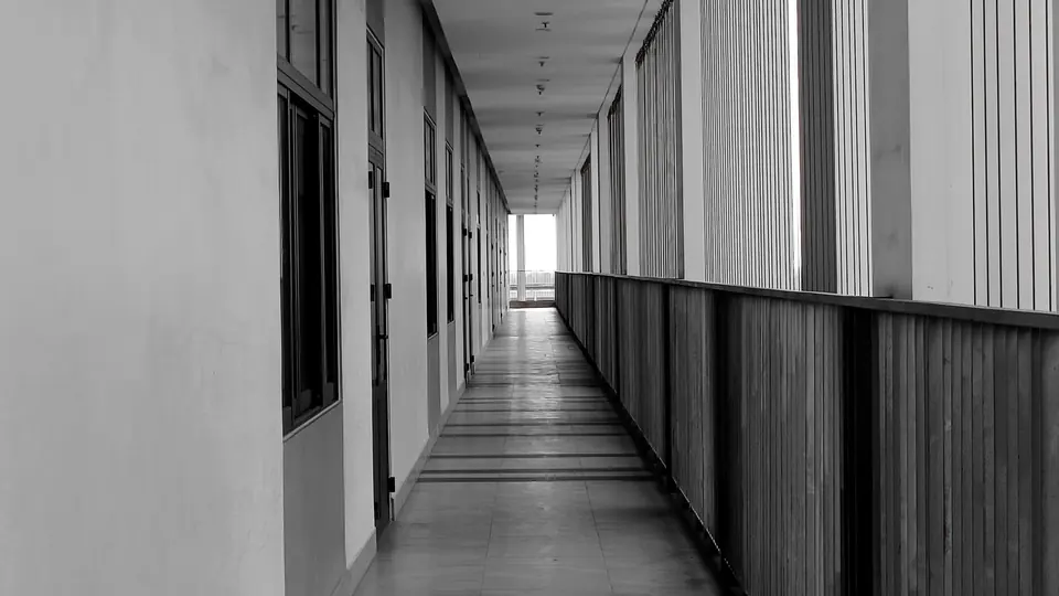 Black and white view along an austere architectural corridor